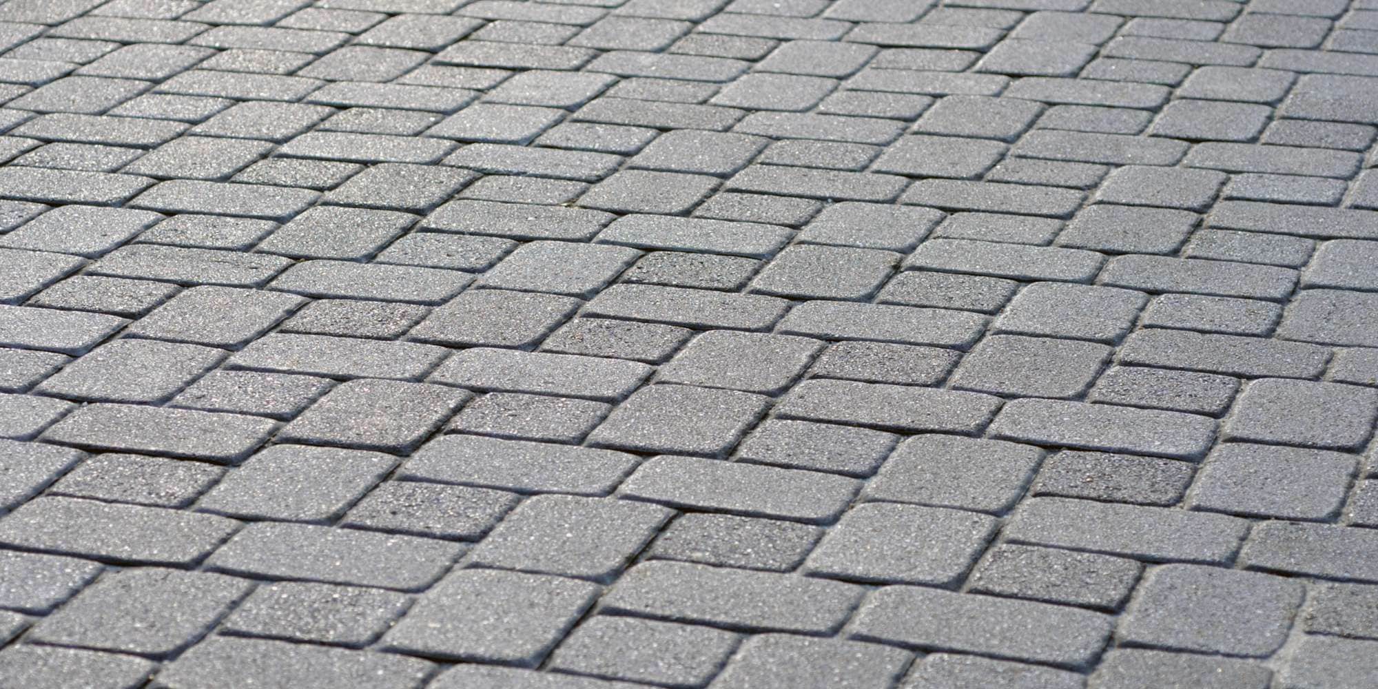 Close-up of gray interlocking rectangular paving stones arranged in a repeating pattern, forming a smooth and even surface—perfect for sidewalks or patios in Maricopa County, AZ. These stones pair well with professional seal coating for added durability.